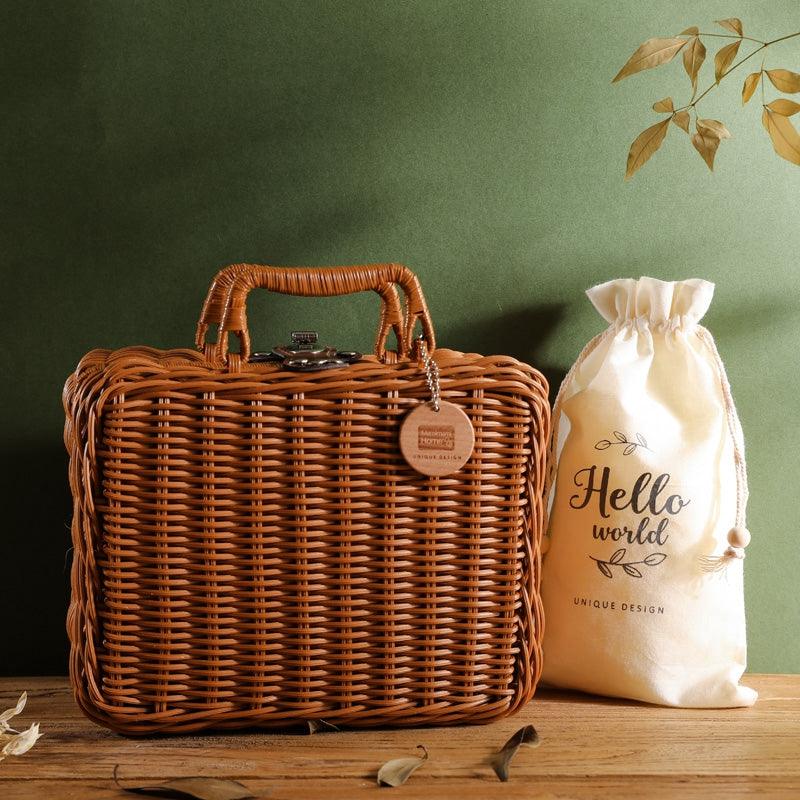 Das Ayla Baby Geschenk zur Geburt von Hello World steht in einem rechteckigen Weidenkorb mit Henkel auf einer Holzfläche, daneben eine cremefarbene "Hello World Unique Design"-Tasche und ein niedlicher Koala-Greifling, eingebettet in ein grünes Blattdekor.