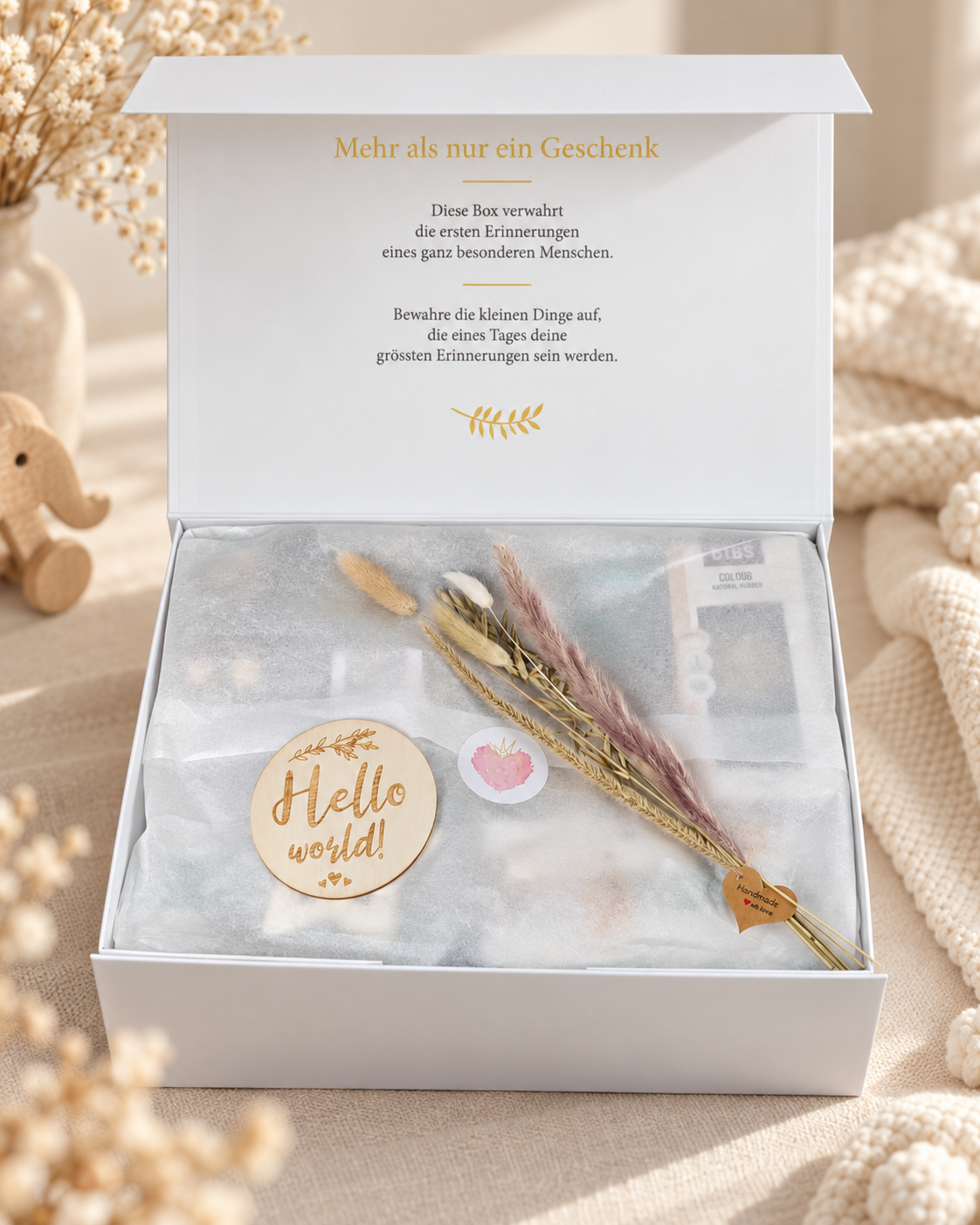 Geöffnete cremeweisse Baby Geschenkbox mit Seidenpapier, Trockenblumen und Erinnerungsaufdruck im Deckel