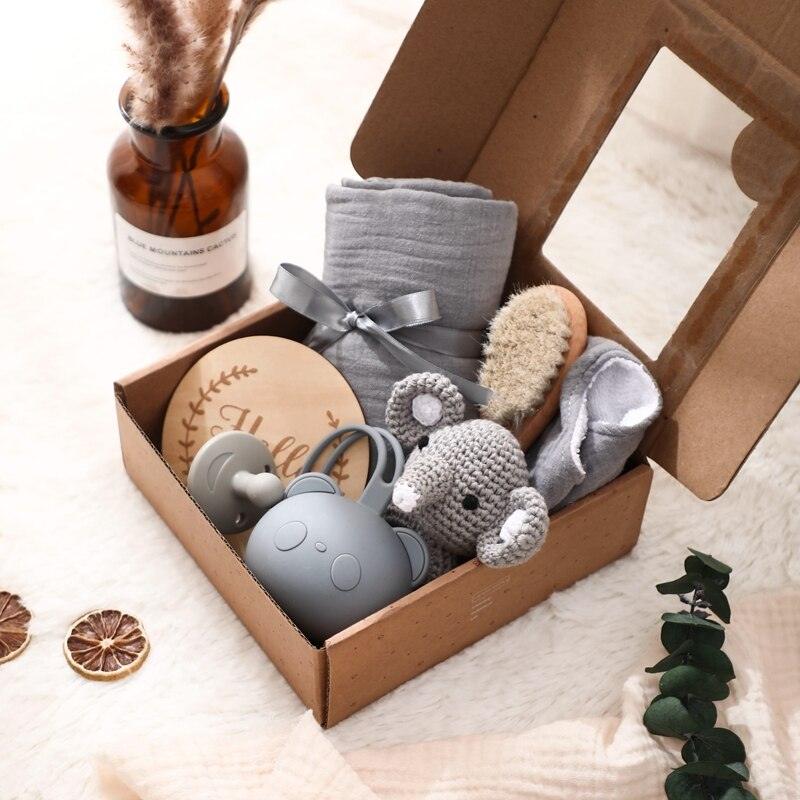 Das Gary Baby Geschenk zur Geburt von Hello World enthält eine graue Babydecke, eine Holzbürste, ein gehäkeltes Koala-Spielzeug, eine graue Schnabeltasse mit Bärenohren, kuschelige Söckchen, ein Hello World Holzschild und ein weiches Multifunktionstuch.