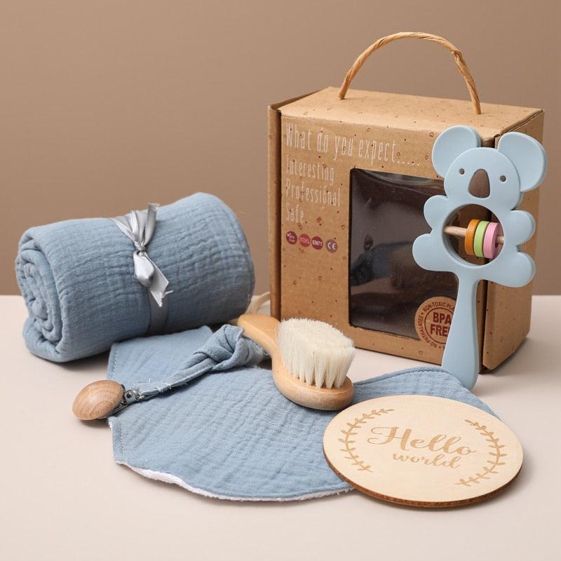 Das Aaron Baby Geschenk zur Geburt von Hello World enthält eine blaue Musselindecke, eine weiche Bürste, eine Koala-Rassel, ein Holzschild "Hello world" und eine Fensterbox - ideal für die ersten Baby-Pflegeutensilien.
