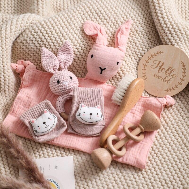 Das Kira Baby Geschenk zur Geburt von Hello World enthält eine weiche Strickdecke, rosa Hasenplüschtiere, ein "Hello World"-Holzschild, Babysocken mit Katzengesichtern, eine Rasselhase und eine sanfte Haarbürste - das perfekte Geschenk für Neugeborene.