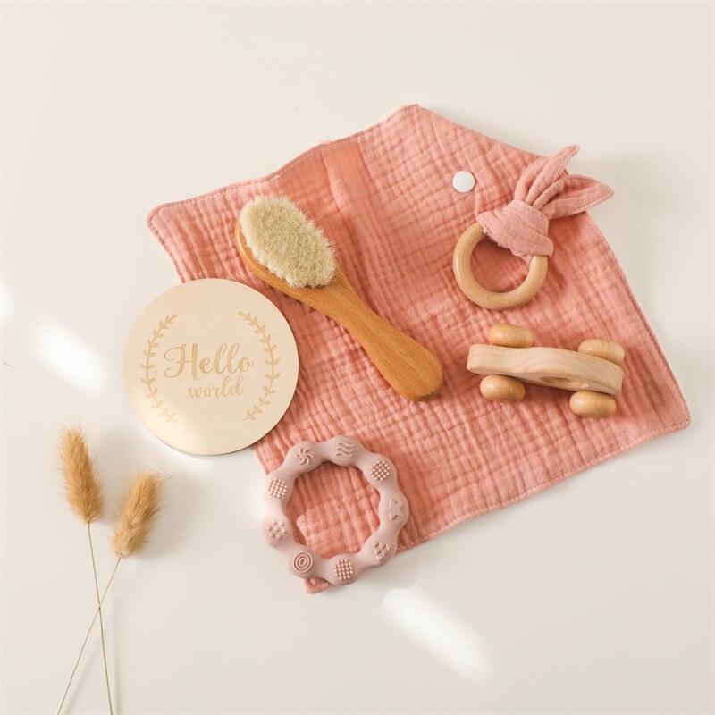 Das Lora Baby Geschenk zur Geburt von Hello World enthält ein weiches rosa Musselintuch, eine Babybürste aus Holz, einen Holz-Greifling, Beißringe, ein rundes "Hello World"-Schild und einen Beißring mit Hasenohren - zauberhaft gestaltet für Neugeborene.