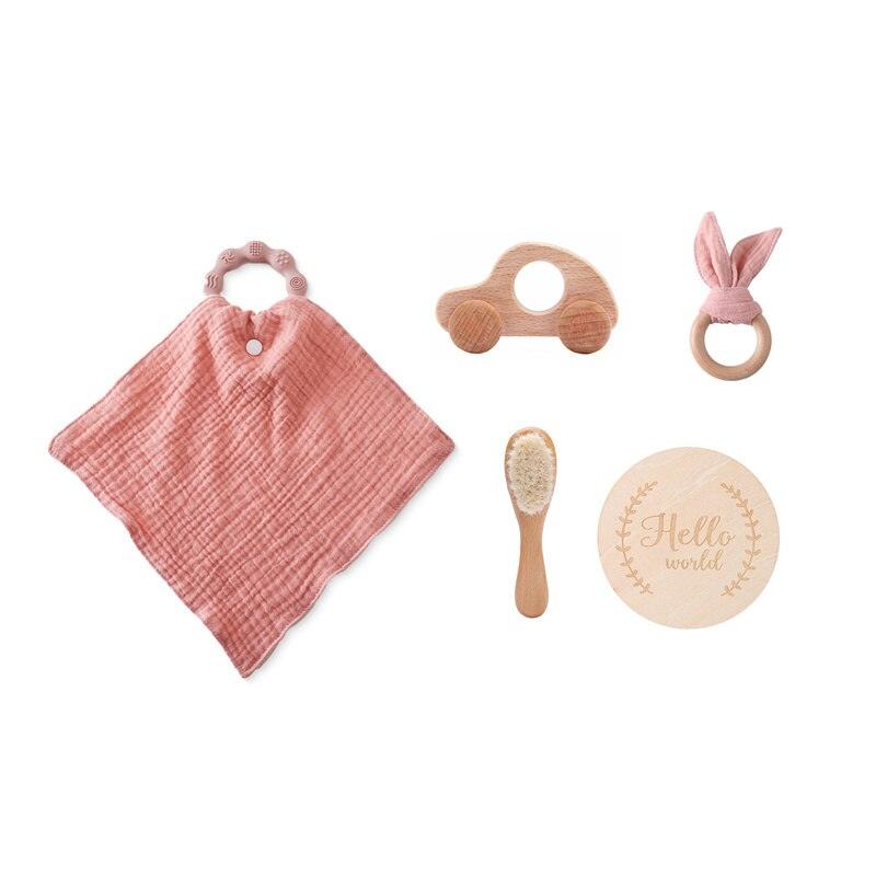 Das Lora Baby Geschenk zur Geburt von Hello World besteht aus einem rosa Musselintuch mit Holz-Greifling, einem Spielzeugauto aus Holz, Beißringen mit rosa Stoff, einer Babyhaarbürste und einer runden "Hello World"-Plakette - perfekt als Geschenk für Neugeborene.