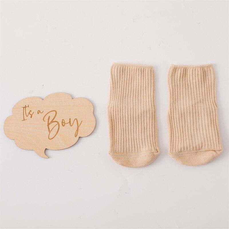 Das Ringo Baby Geschenk zur Geburt von Hello World zeigt ein Sprechblasen-Holzschild mit "It's a Boy" neben beigen Babysöckchen - ideal für das Jungen Geschenkset oder als liebevolles Geschenk zur Geburt.