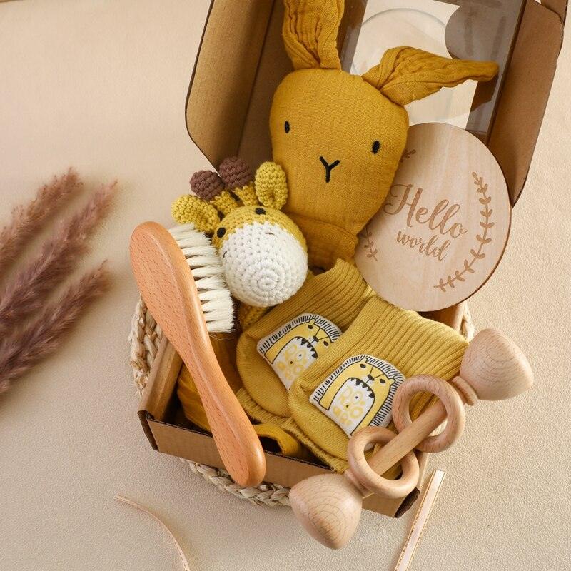 Das Shania Baby Geschenk zur Geburt von Hello World ist eine bezaubernde Geschenkbox mit einem gelben Plüschhasen, einer gehäkelten Rasselgiraffe, einer Holzbürste und Rassel, Babykleidung mit Giraffendruck und einer "Hello World"-Scheibe - das perfekte nachhaltige Babygeschenk.