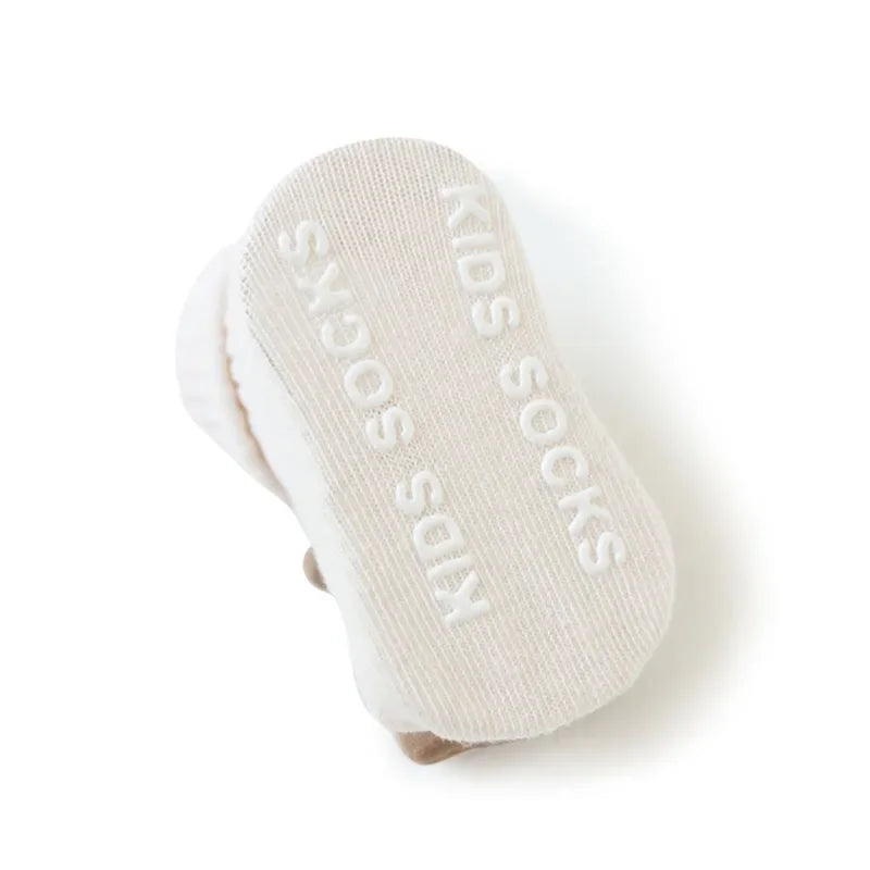 Die Hello World Socken Bär (Sohle: 6x11cm) für 6-12 Monate ist eine weiße, rutschfeste Kindersocke mit "KIDS SOCKS" in erhabenen weißen Buchstaben und einem niedlichen Bärendesign, das von handgefertigten Babysocken inspiriert ist.