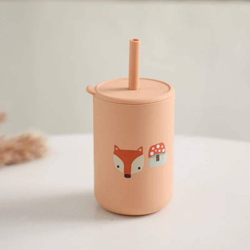 Der Hello World Trinkbecher mit Motiv Orange (6x12,5cm), ein BPA-freier Silikon Kindertrinkbecher mit Deckel und Strohhalm, ist mit einem Fuchs-Design und rot-weißem Pilzmotiv versehen und steht auf einer weißen Oberfläche.