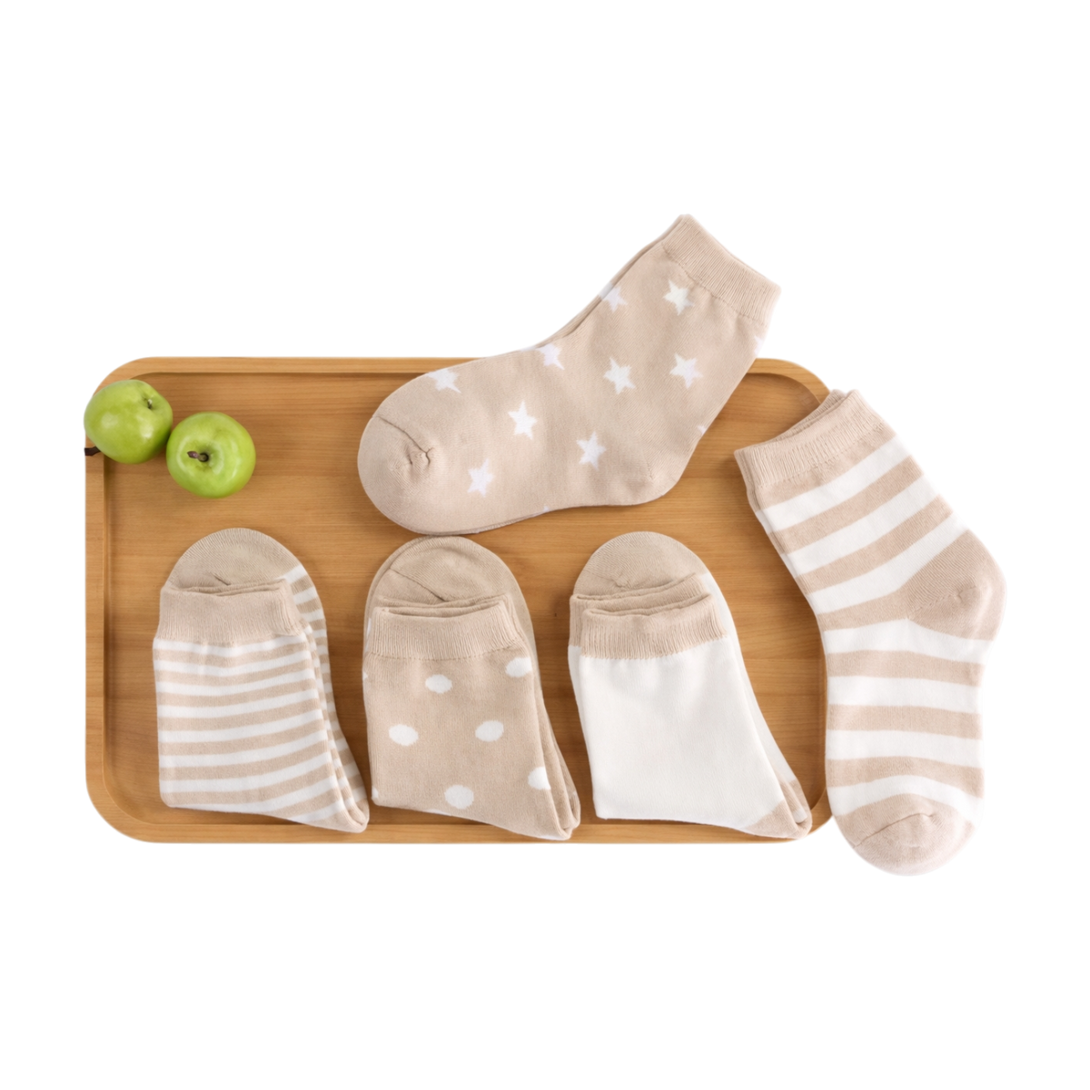 Das "Kuschelkörbchen Sternenfünflinge" von Hello World besteht aus einem Holztablett mit zwei grünen Äpfeln und fünf Paar beigen und weißen Sternen-, Streifen-, Polka-Dot- und einfarbigen Söckchen - ein niedliches Baby-Geschenkset auf weißem Hintergrund.