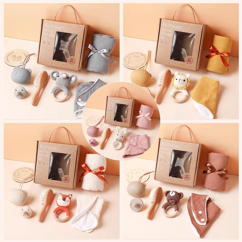Vier Leonie Baby Geschenk zur Geburt Geschenkboxen von Hello World sind erhältlich, jeweils mit Box, Kuscheltier, Schnuller-Set, Bürste, Tuch und Badefäustling in den Farben grau, gelb, rosa oder braun - ideale Geschenke für Neugeborene.