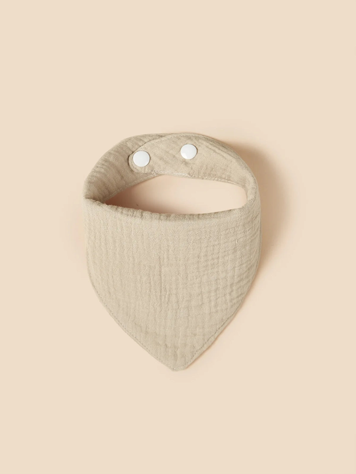 The Hello World Cotton Khaki Bib is a beige khaki bib with two white snaps, shown flat on a tan background.