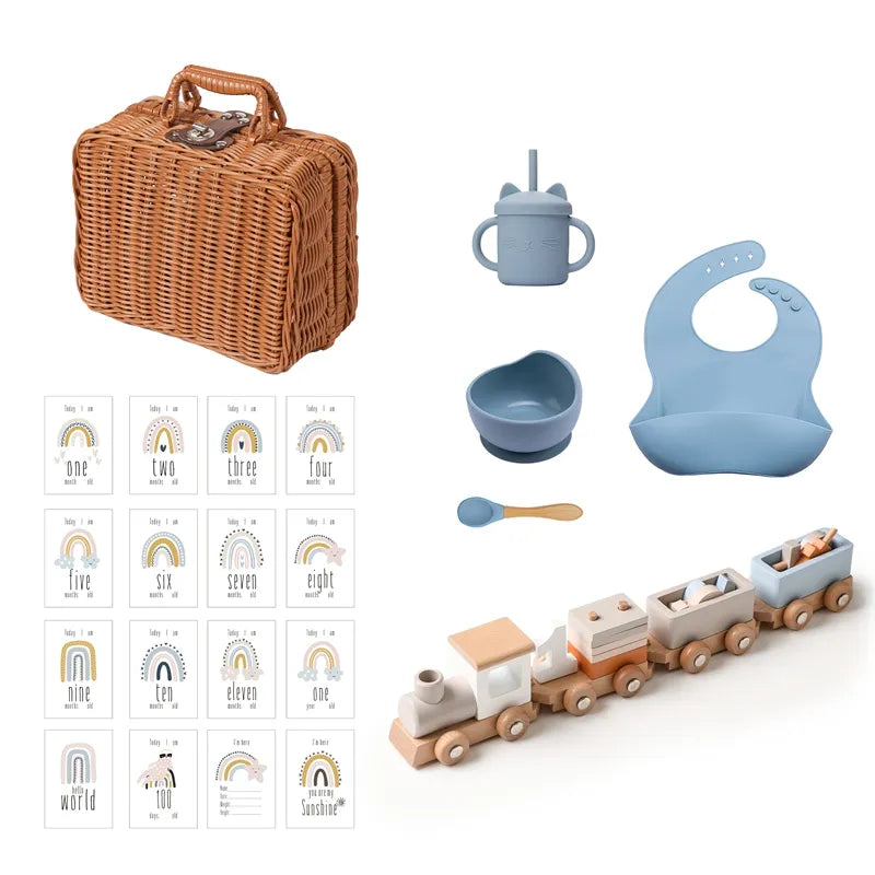Das Hello World Thomas Baby Geschenk zur Geburt enthält einen Weidenkorb, ein blaues Silikonlätzchen, eine Tasse, eine Schüssel mit Löffel, eine Spielzeugeisenbahn aus Holz und Regenbogen-Meilensteinkarten - perfekt, um bleibende Familienerinnerungen zu schaffen.