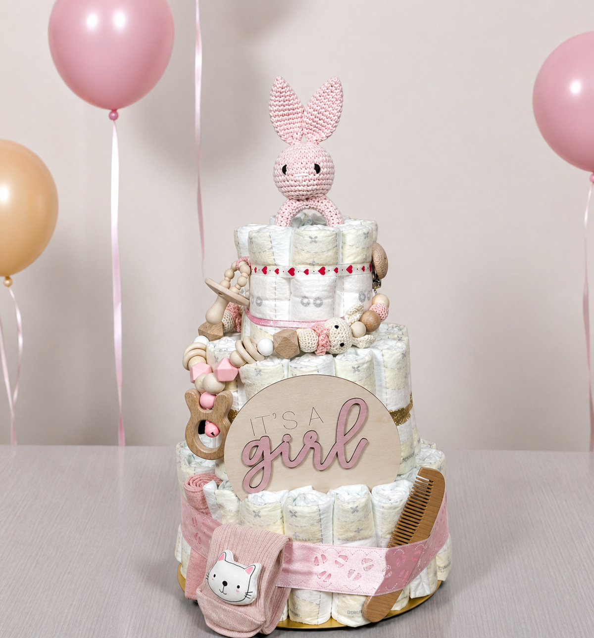Rosa Windeltorte It’s a Girl mit Kuscheltier und Babyaccessoires