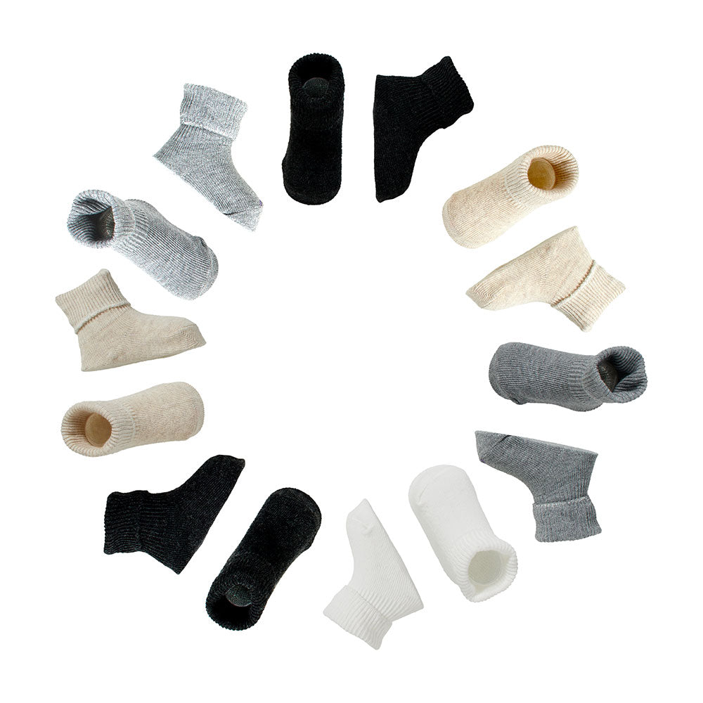 Sieben Paar Unisex Baumwollsocken für Babys kreisförmig in neutralen Farben angeordnet