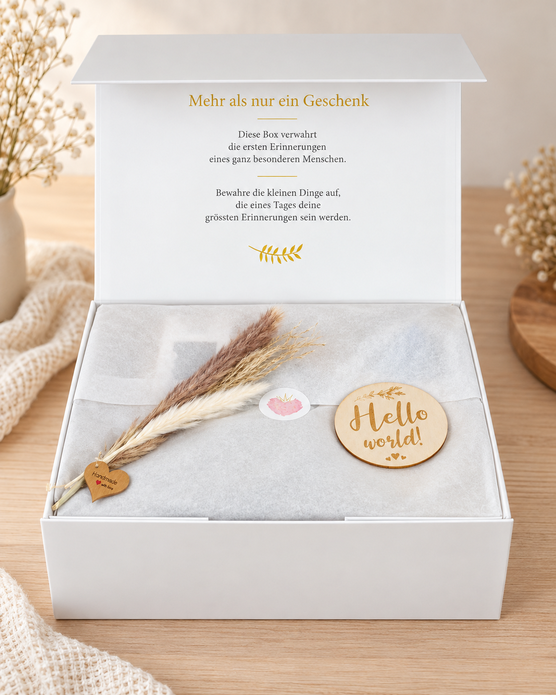 Opened cream-white premium gift box for the birth with a commemorative print on the lid, tissue paper, dried flowers and a wooden sign “Hello world!”