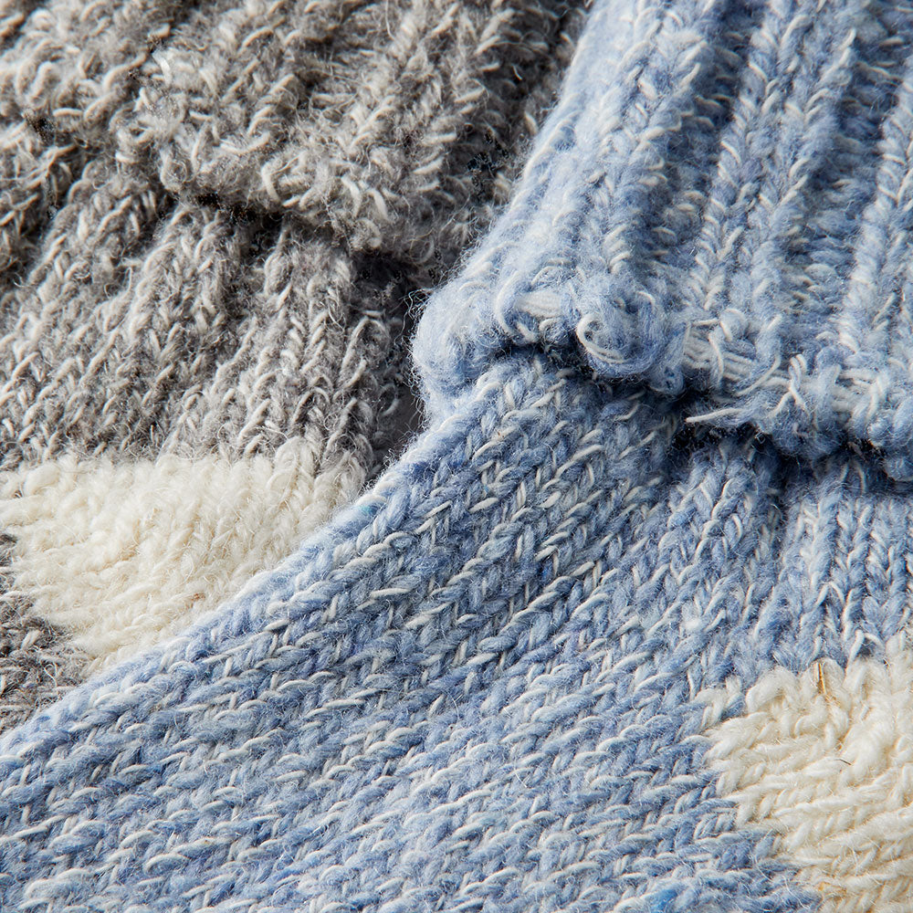 Detailaufnahme der gestrickten Babysocken mit Wolle in Blau und Grau
