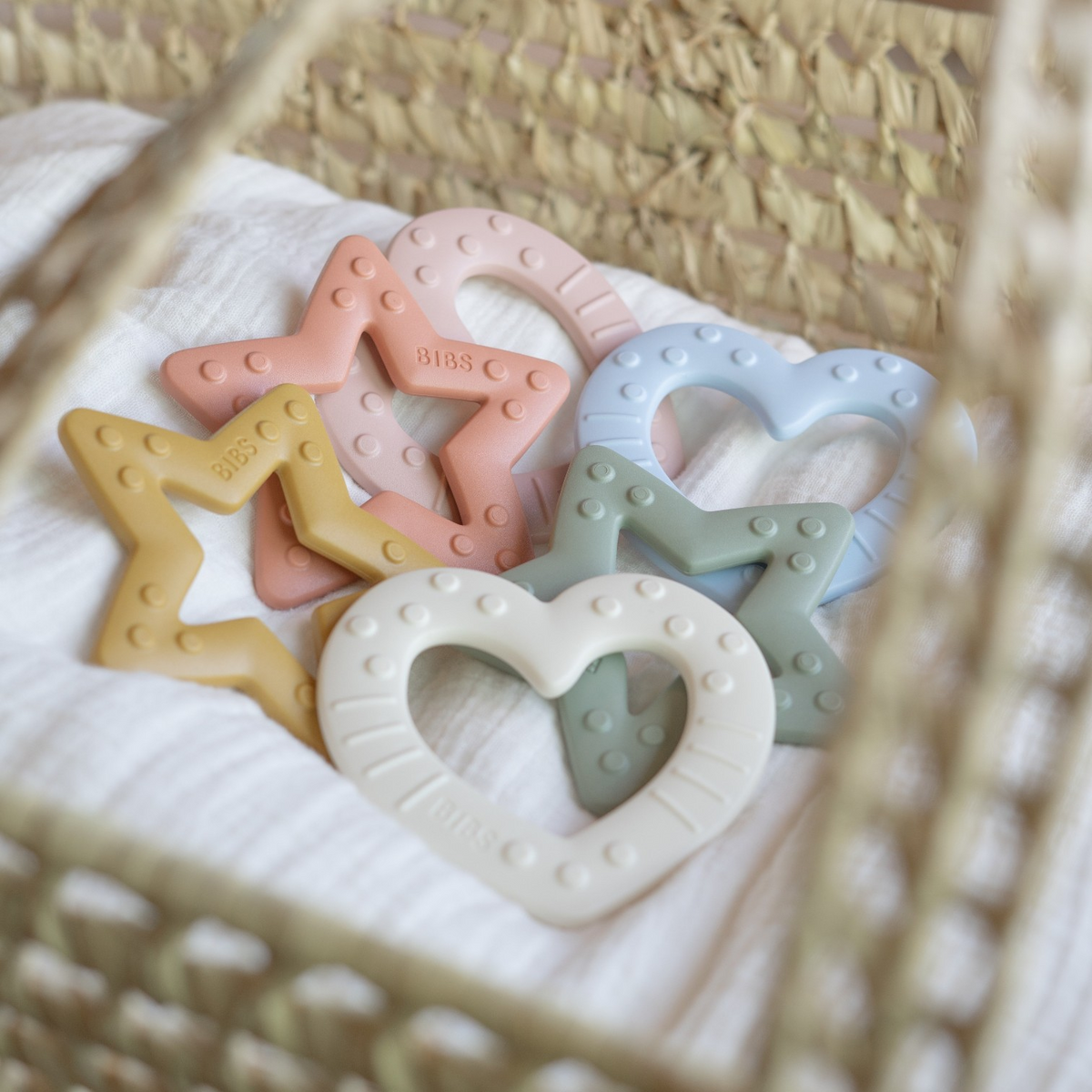 Bunte Stern- und Herz-Beissringe für Babys in verschiedenen Farben in einem geflochtenen Korb