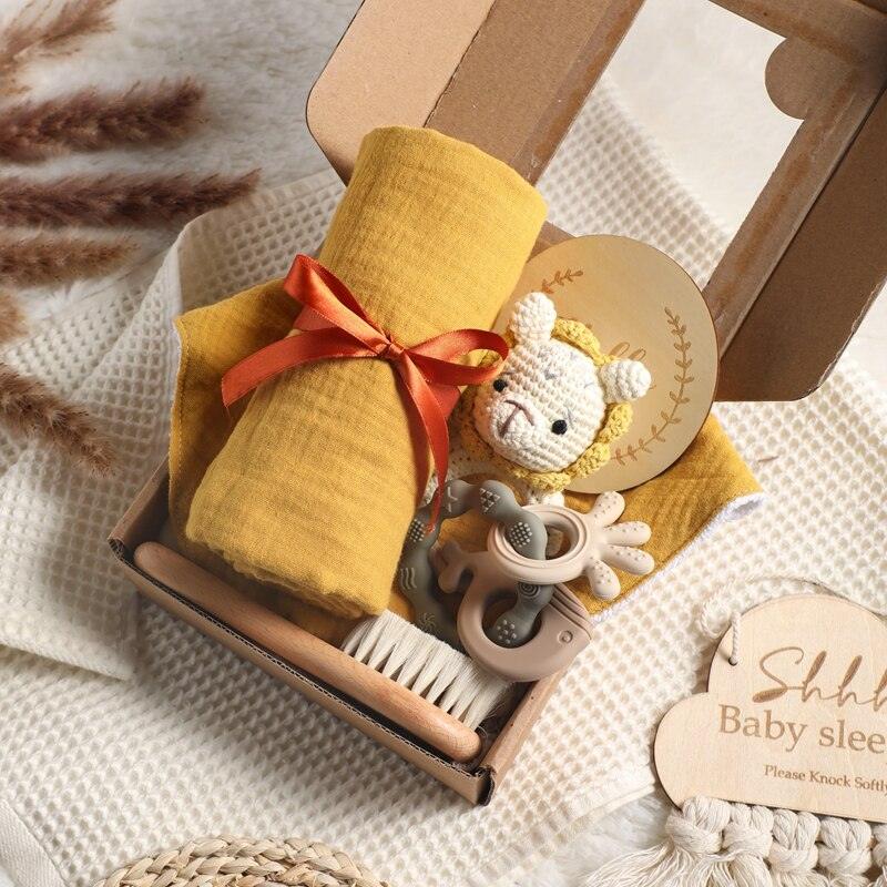 Das Ciara Baby Geschenk zur Geburt von Hello World enthält ein gelbes Musselintuch, einen gehäkelten Rassellöwen, eine Zahnungshilfe, Holzbürste, rundes Holzschild und eine weiche cremefarbene Decke.