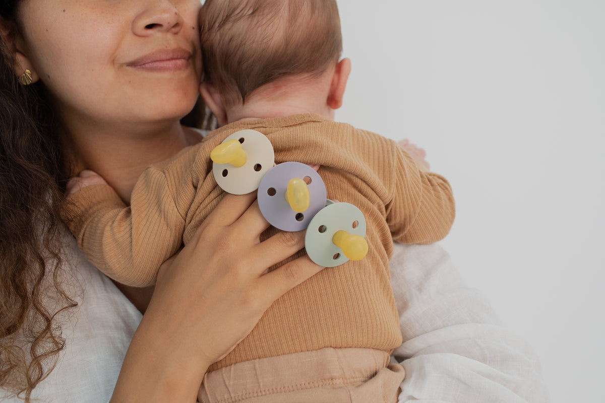 Baby mit Colour Schnullern aus natürlichem Gummilatex in verschiedenen Farben