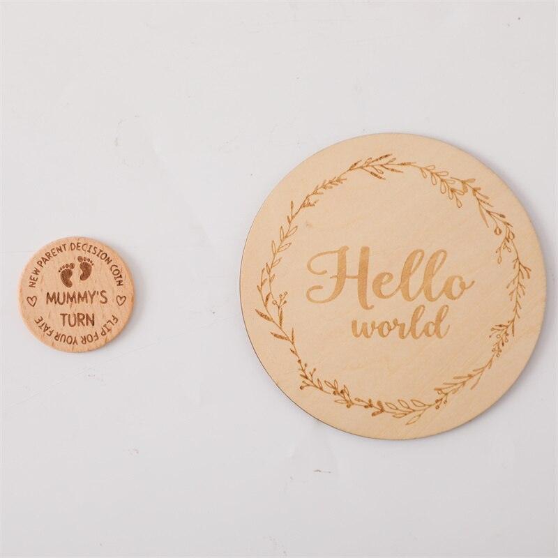 Zwei runde Holztafeln aus dem Fiodor Baby Geschenk zur Geburt der Marke Hello World auf weißem Hintergrund: auf der einen steht "Hello world" mit einem Blattrand, auf der anderen "Mummys turn" - ein schönes Geschenk für frischgebackene Eltern.