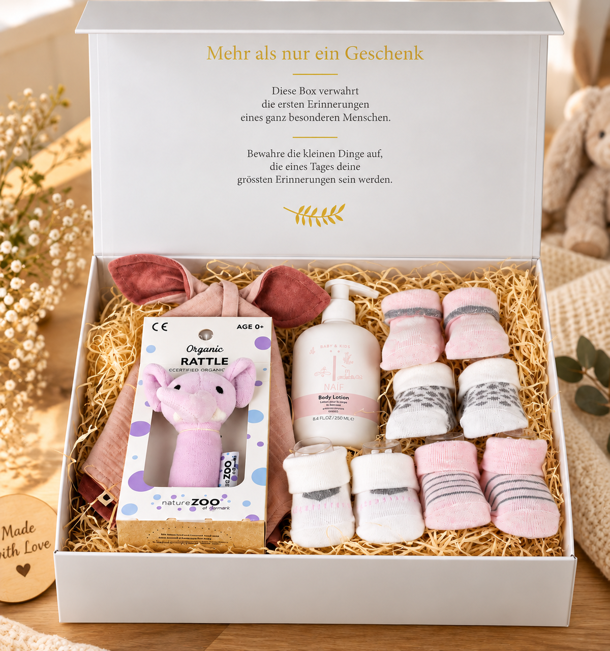 Offene Baby Geschenkbox Eva mit Bio Babyrassel Elefant, roséfarbenem Bio-Baumwoll Kuscheltuch, Babysocken 4er-Set und NAÏF Bodylotion