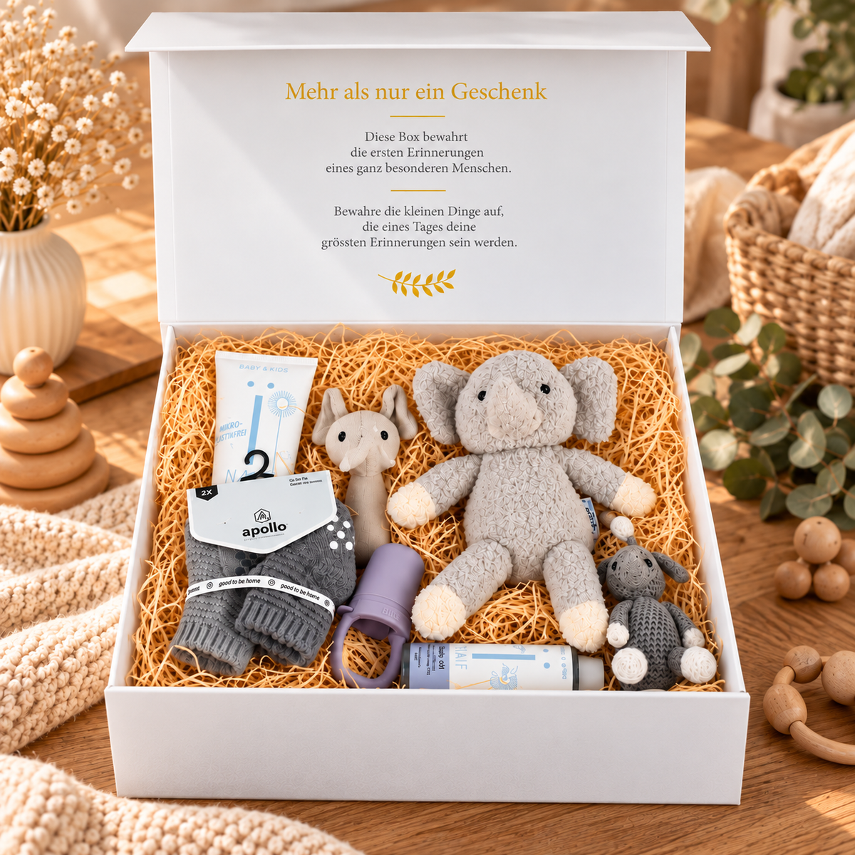 Open baby gift box Julian with gray organic elephant, stroller trailer, baby socks, BIBS baby feeder as well as NAÏF washing gel and bath oil