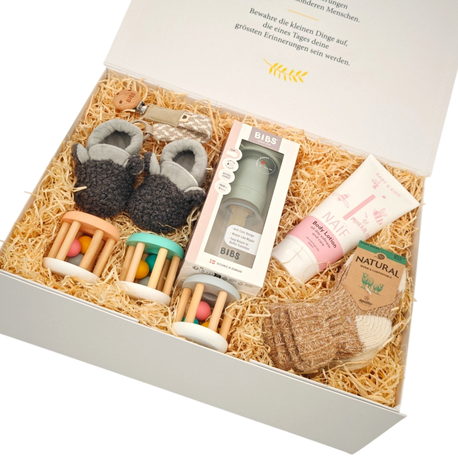 Geschenkbox Mika in Schrägansicht mit weichen Babyschuhen, ausgewähltem Babyzubehör, Pflegeprodukt und liebevoll arrangierten Geschenken in einer hochwertigen Magnetbox.
