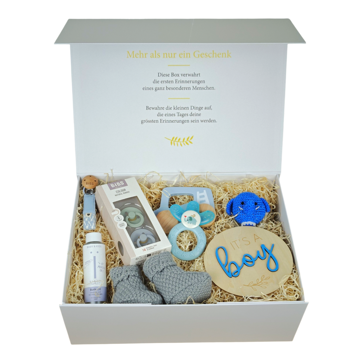 Raphael gift box for babies in blue and gray with BIBS pacifiers, pacifier chain, crocheted elephant rattle, knitted baby shoes, cooling teething ring, wooden car, NAÏF bath oil and wooden sign “It’s a boy” in a cream white magnetic box.