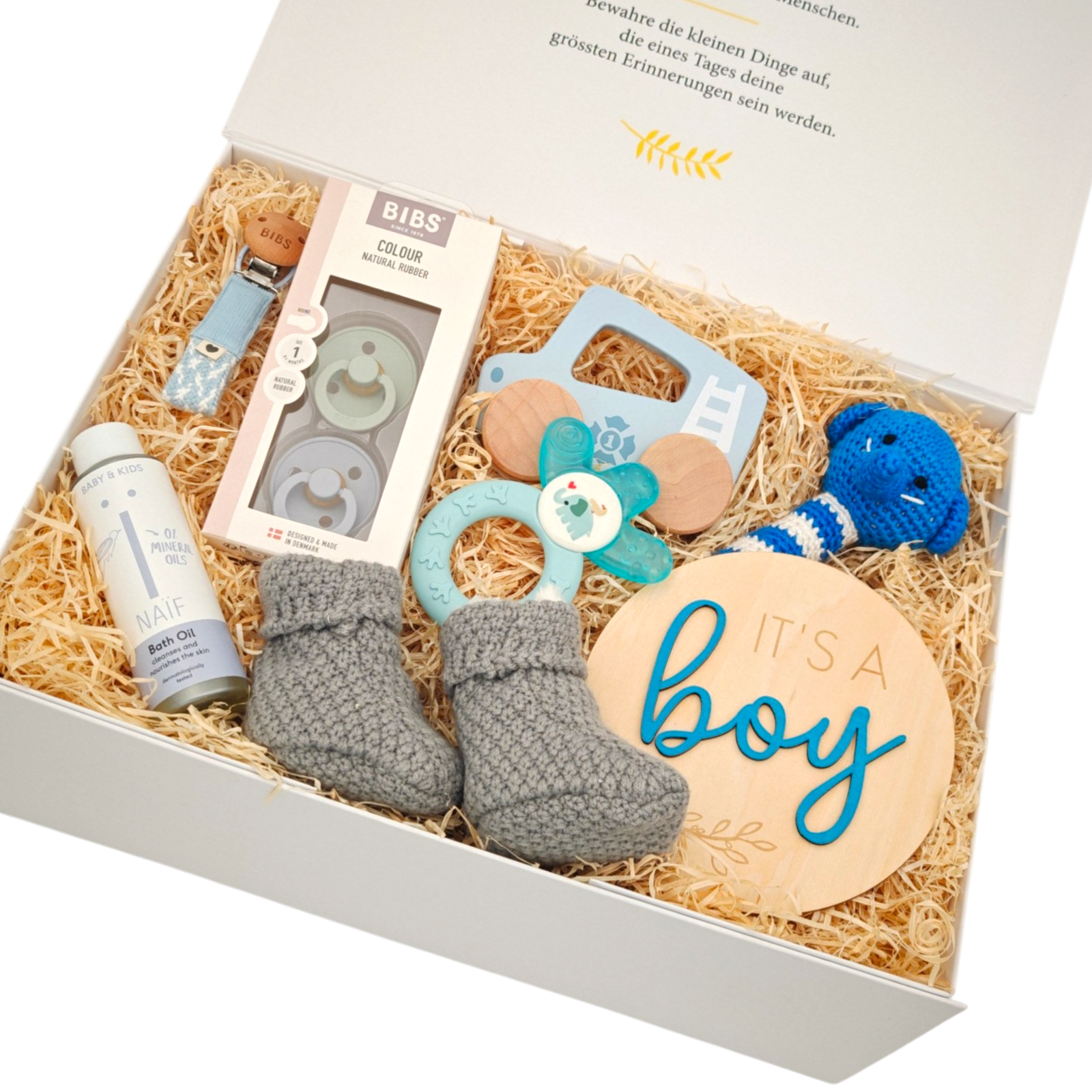 Geschenkbox Raphael in Schrägansicht mit Babyschuhen, BIBS Schnuller, Babyspielzeug, Pflegeprodukt und Holzschild "It's a boy" in einer hochwertigen Magnetbox.