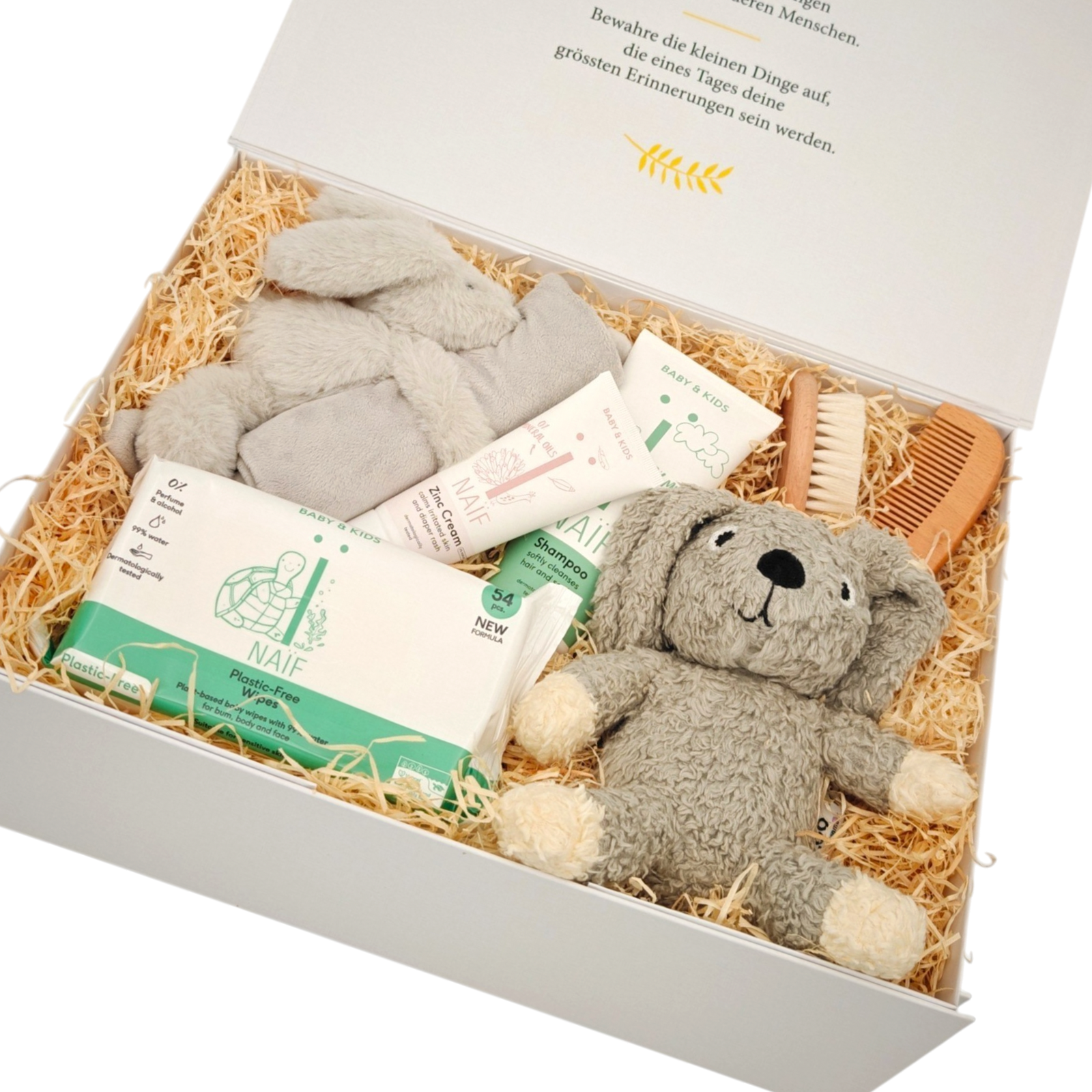 Geschenkbox Ruben in Schrägansicht mit grauem Kuschelbär, weichem Schmusetuch und NAÏF Babypflegeprodukten, liebevoll auf Holzwolle in einer hochwertigen Magnetbox arrangiert.
