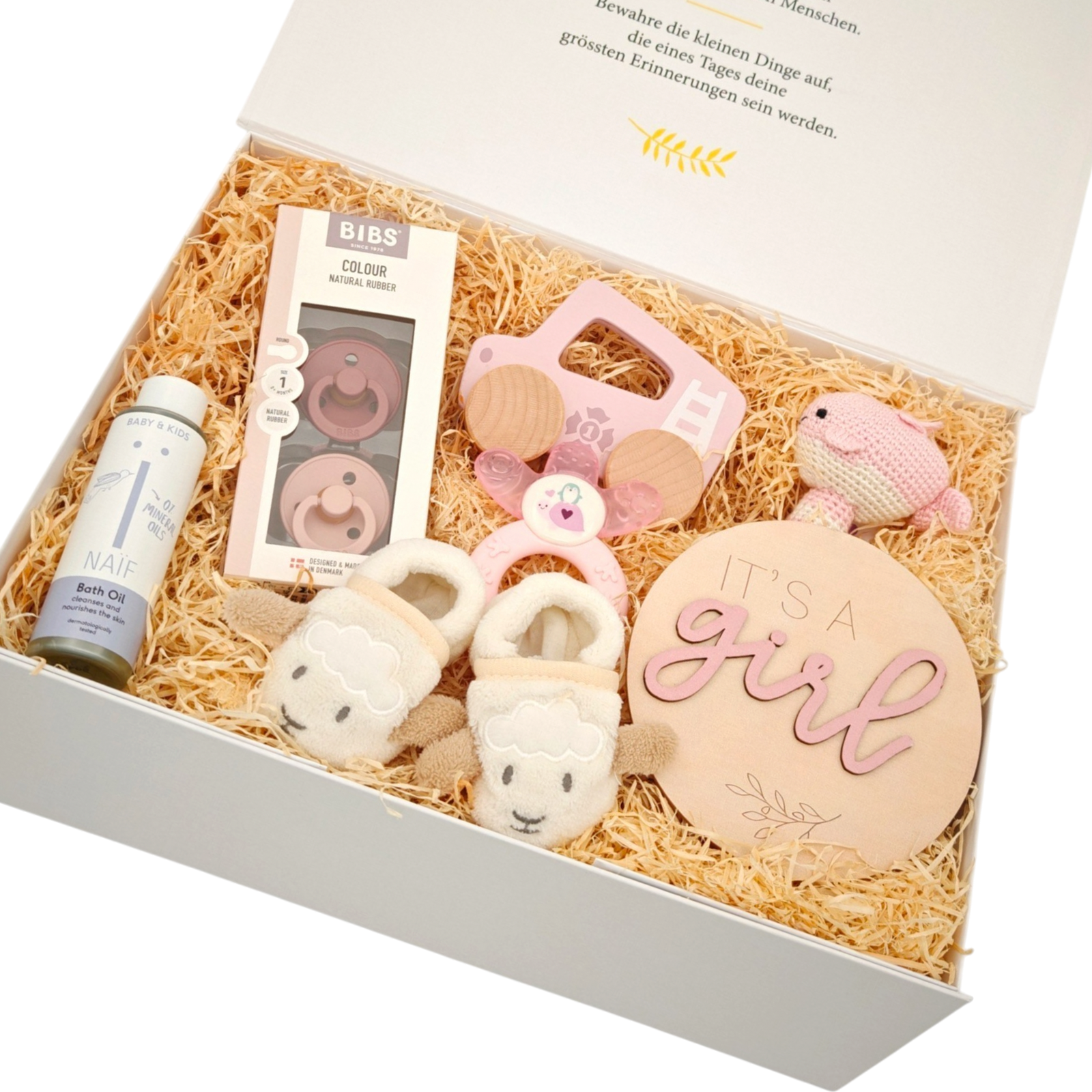 Geschenkbox Tiffany in Schrägansicht mit BIBS Schnullern, weichen Babyschuhen, rosa Babyspielzeug und Holzschild «It's a girl» in einer hochwertigen Magnetbox.