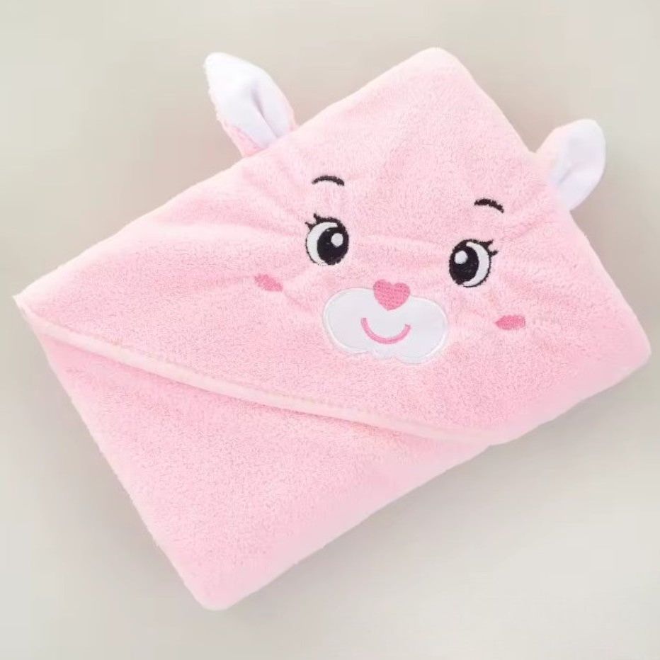 Das Hello World Badetuch mit Kapuze Hase [80x80cm] ist ein rosafarbenes Babyhandtuch mit gesticktem Tiergesicht, lachenden Augen, einer herzförmigen Nase und zwei Ohren an der Kapuze.