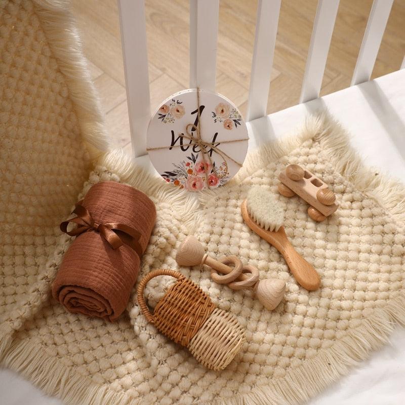 Schaffen Sie eine gemütliche Umgebung für Ihr Baby mit dem Carla Baby Geschenk zur Geburt von Hello World: strukturierte beigefarbene Matte, braune Windel, Weidenkorb, Holzrassel für sensorische Entwicklung, Bürste, Spielzeugauto und geblümte 1-Wochen-Plakette - perfekt für die Nähe des Kinderbettes.