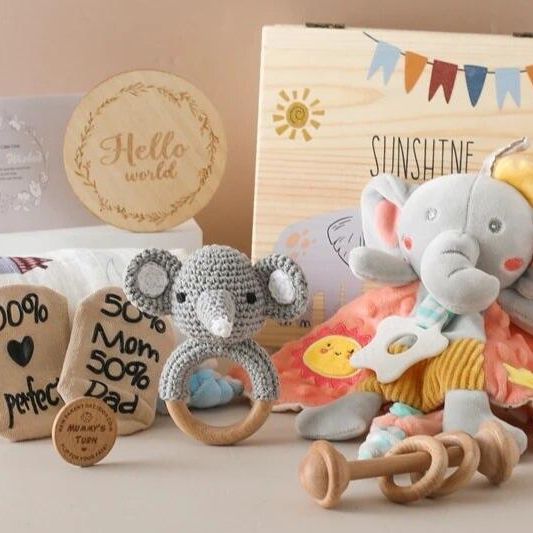 Das Cyrill Baby Geschenk zur Geburt von Hello World ist ein entzückendes Geschenkset für Neugeborene mit einem Plüschelefanten, einem gehäkelten Koala-Ring, Holzspielzeug, kuscheligen Socken, einer Hello World-Karte, einer bedruckten Decke und einer Aufbewahrungsbox mit Sonne und Wimpel.
