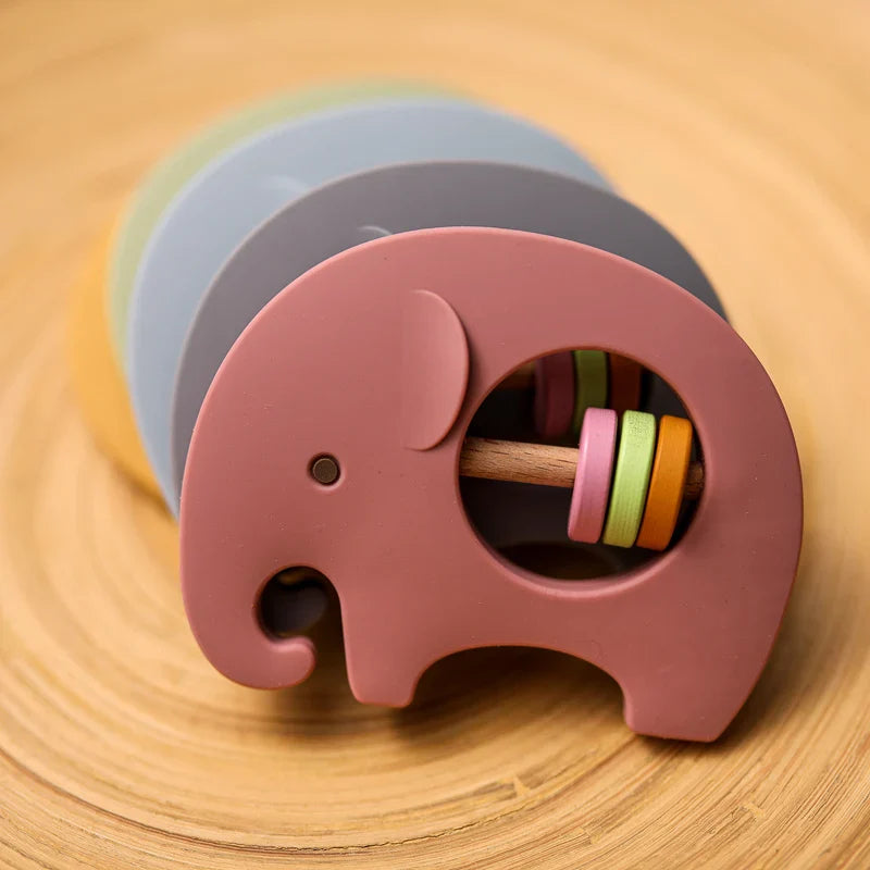 Ein farbenfrohes Elefant Rosa aus Silikon [9x6.8cm] von Hello World, ideal als perfektes Geschenk für Kinder, präsentiert auf einer Holzoberfläche mit konzentrischen Mustern.