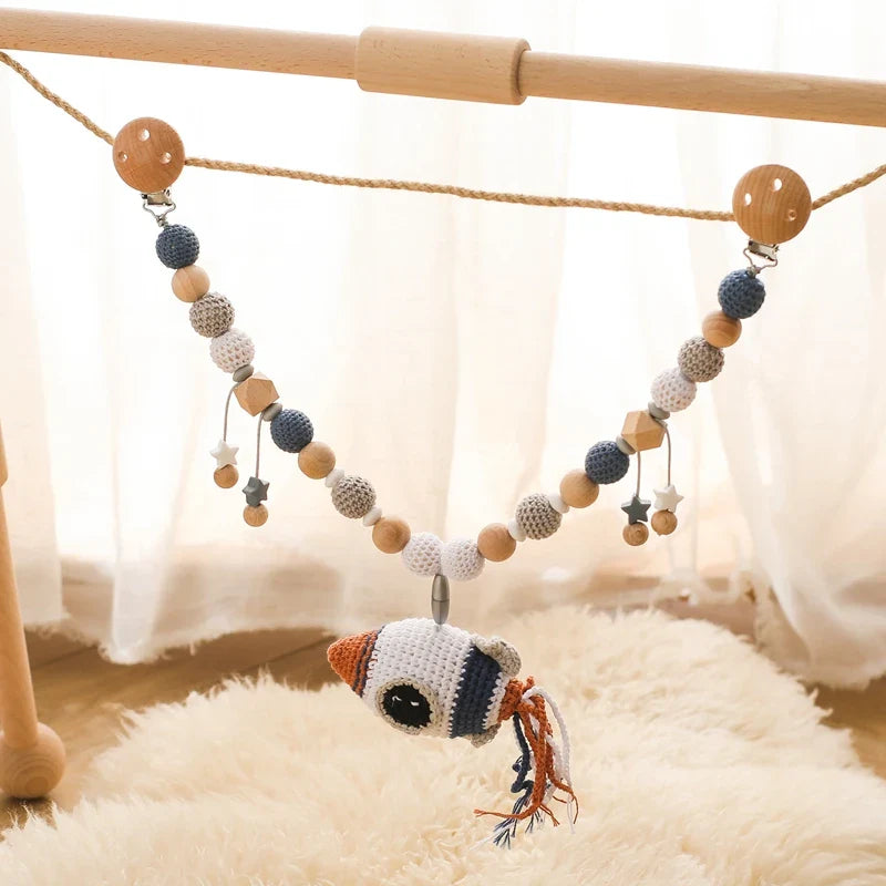 Die Hello World Kinderwagenkette Rakete [30x38cm] besteht aus gehäkelten und hölzernen Perlen, kleinen Holzfiguren und einer Rakete - ein ideales Baby Weltraum Spielzeug für Spielhallen oder Kinderwagen.