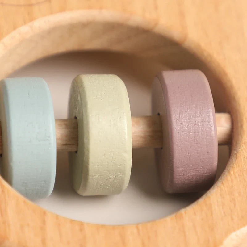 Nahaufnahme des Koala aus Holz [7x15cm] von Hello World - drei Holzperlen in Blau, Hellgrün und Mauve auf einem Stab, der teilweise von einer kreisförmigen Öffnung umrahmt wird. Ein schönes Beispiel für nachhaltiges Spielzeug mit australischem Design.