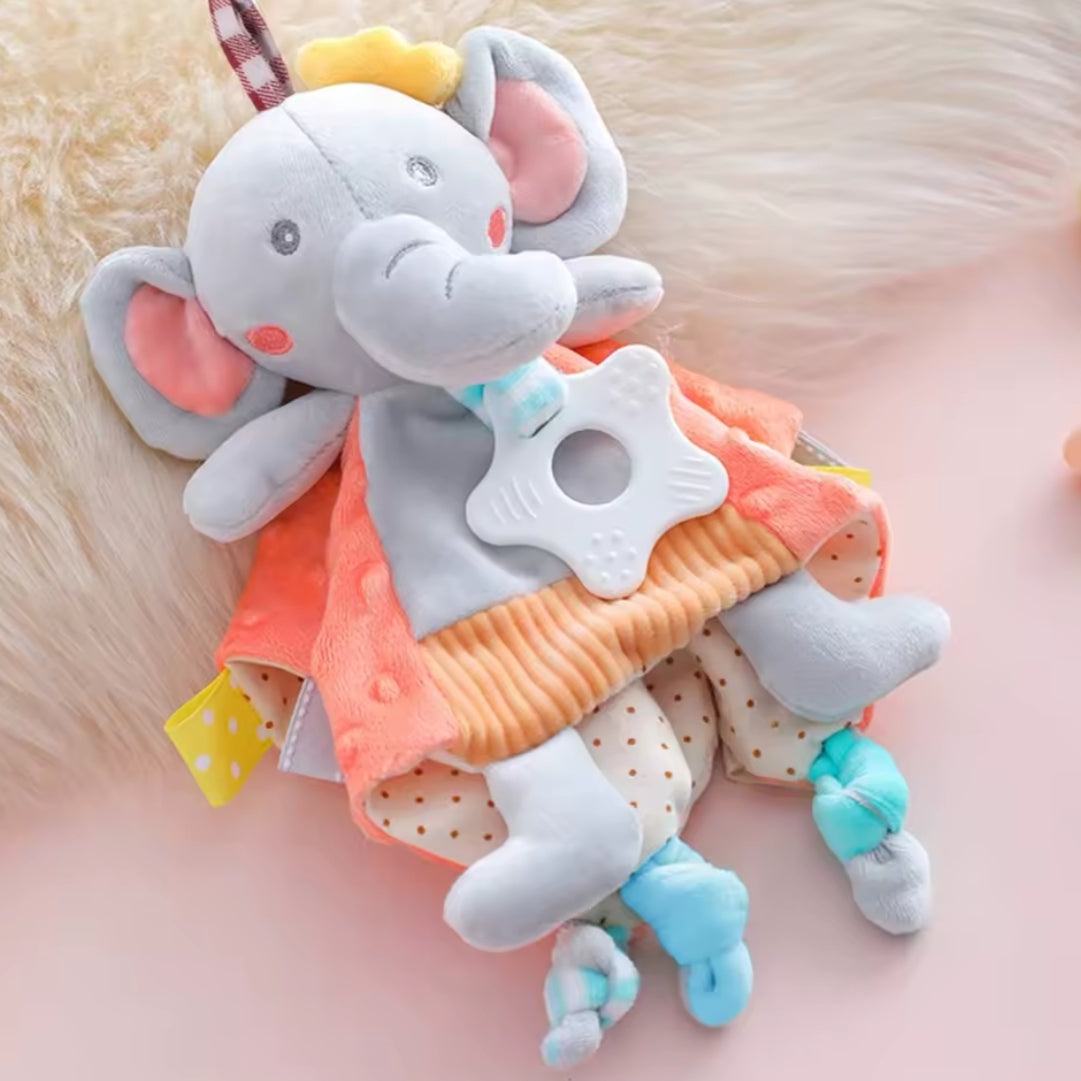 Das Hello World Kuscheldreieck Elefant [30x30cm] hat große rosafarbene Ohren, eine gelbe Krone, bunte, strukturierte Stoffe und hält einen weißen Beißring, was es zu einem weichen und plüschigen Babyspielzeug macht, das perfekt zum Kuscheln ist.
