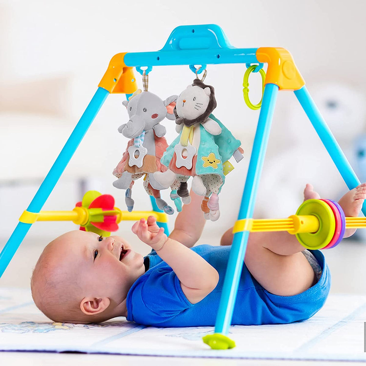 Ein Baby liegt auf einer Spielmatte und lächelt das Hello World Kuscheldreieck Löwe [30x30cm] an - eine kuschelige Angelegenheit und perfekte Kinderzimmer Deko für die Kleinen.