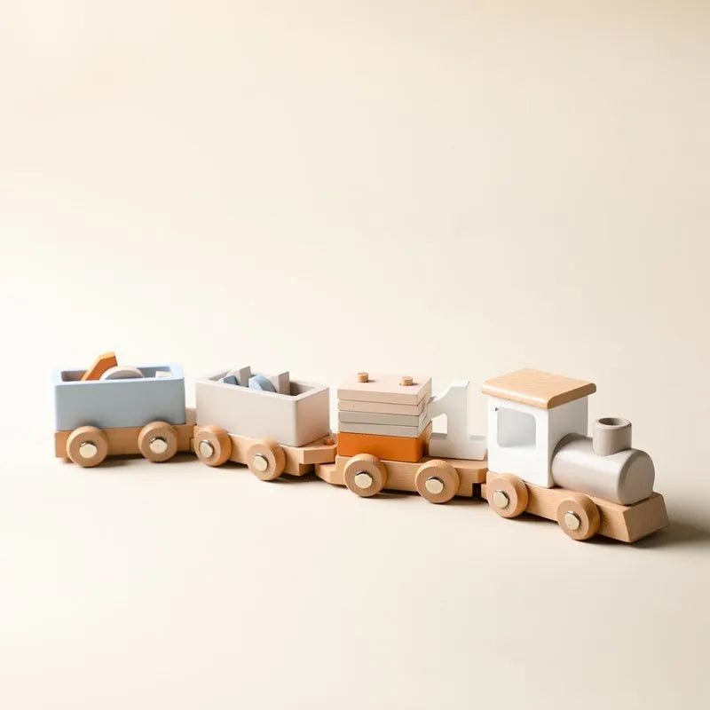 Die Hello World Lokomotive aus Holz [34,5x6,4cm] ist eine pastellblaue, weiße und naturfarbene Spielzeugeisenbahn aus Holz mit drei Waggons und stapelbaren Blöcken, die zu spielerischen Eisenbahn-Abenteuern anregt. Abgebildet auf einem hellbeigen Hintergrund.