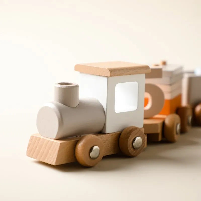 Die Hello World Lokomotive aus Holz [34,5x6,4cm], hergestellt aus nachhaltigem Naturholz in Natur- und Weißtönen, zeichnet sich durch runde Räder und ein minimalistisches Design aus, das auf einer hellen Fläche mit verschwommenem Hintergrund dargestellt wird.
