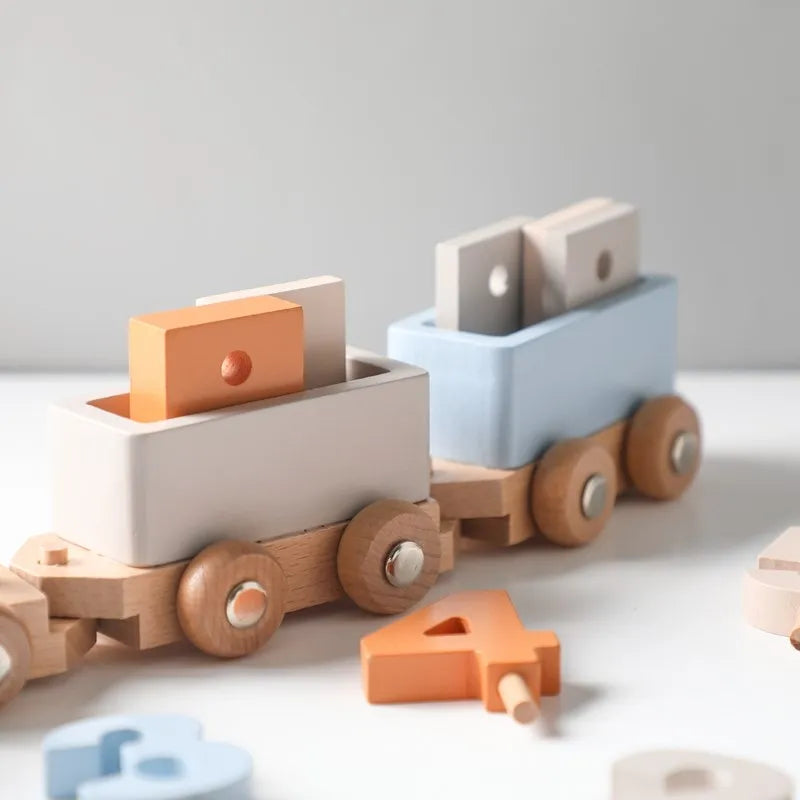 Hello World's Lokomotive aus Holz [34,5x6,4cm]: Zwei Holzeisenbahnwagen, ein weißer und ein blauer, mit pastellfarbenen Zahlen- und Formenblöcken laden zu spielerischen Abenteuern ein, während zusätzliche Zahlenblöcke auf einer weißen Oberfläche für endlosen Spaß sorgen.