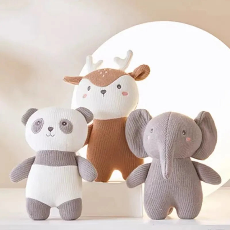 Drei weiche Hello World-Plüschtiere - ein Plüschtier Panda [18x14cm], ein Hirsch mit Geweih und ein Elefant mit großen Ohren - stehen nebeneinander vor einem sanft beleuchteten, hellen Hintergrund.