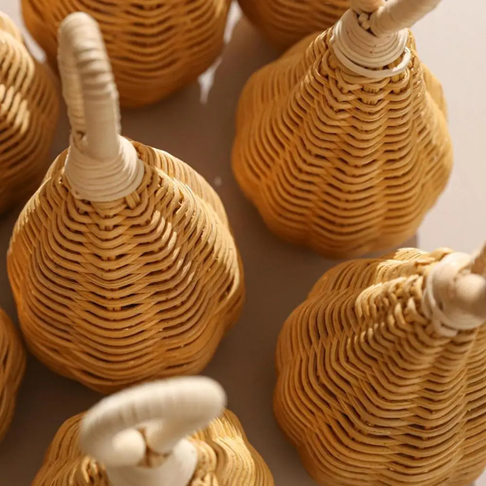 Nahaufnahme mehrerer Hello World Rassel Rattan [8x17cm] mit gebogenen Griffen, die weiche Schatten auf eine helle Oberfläche werfen. Diese natürlich hellbraunen Instrumente haben eine abgerundete, strukturierte Optik.