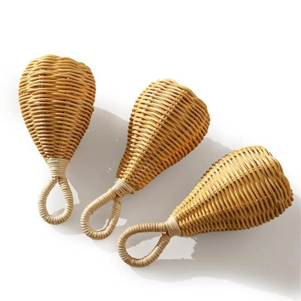 Drei Rassel Rattan [8x17cm] von Hello World mit geschlungenen Griffen liegen auf weißem Hintergrund und werfen sanfte Schatten - handgefertigt, nachhaltig und als Musikinstrument vielseitig einsetzbar.