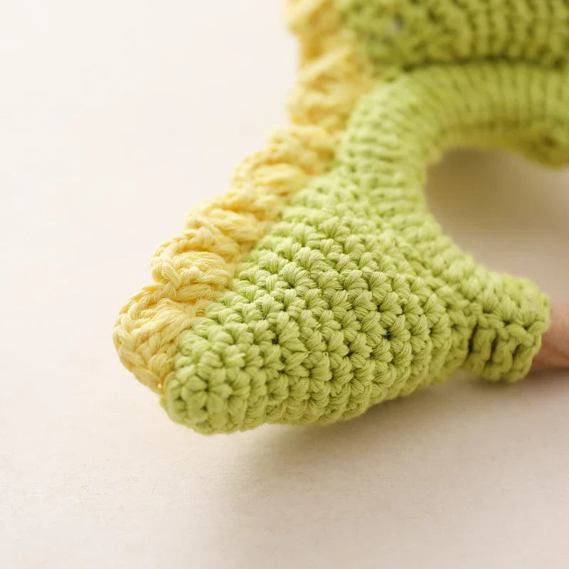 Nahaufnahme eines handgefertigten Rasseltier Dino [10x14cm] von Hello World: gehäkelter grüner und gelber Dinosaurierschwanz mit gelbem Muschelsaum, detailreicher Struktur - einzigartiges Dinosaurier Spielzeug.