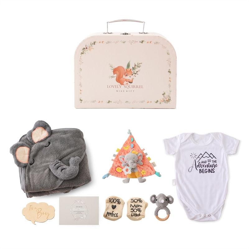 Das Hello World Ringo Baby Geschenk zur Geburt Set besteht aus einem dekorativen Koffer, einem grauen Rassel-Elefanten-Kapuzenhandtuch, einem Dreiecksplüsch, einem Bodysuit "Und so beginnt das Abenteuer", hölzernen Meilensteinscheiben und einem Koala-Beißring - ideal als Jungen Geschenkset.