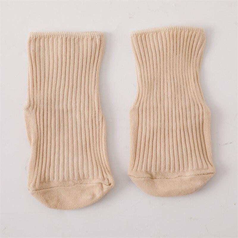 Ein Paar beigefarbene, gerippte, knöchellange Socken aus dem Ringo Baby Geschenk zur Geburt von Hello World liegt flach auf einer weißen Fläche - ideal als Teil eines Jungen Geschenksets oder als Geschenk für Neugeborene.