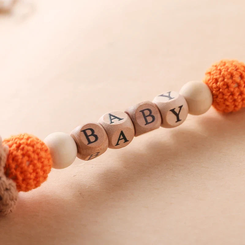 Eine Nahaufnahme der Hello World Schnullerkette mit Aufschrift "Baby" Fuchs [30x4,5cm] mit Holzwürfeln mit der Aufschrift "BABY", orangefarbenen gehäkelten und einfarbigen Perlen sowie einem süßen Fuchsmotiv auf neutralem Hintergrund.