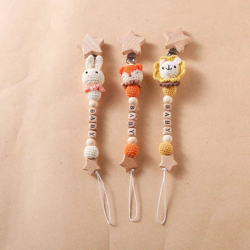 Die Hello World Schnullerkette mit Aufschrift "Baby" Fuchs [30x4,5cm] ist mit einem hölzernen Sternclip und niedlichen Tierperlen versehen und kombiniert Sicherheit und Stil für den Schnuller Ihres Babys auf einem neutralen Hintergrund.