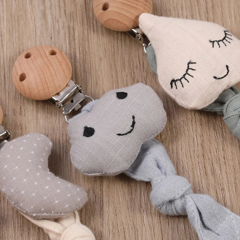 Die "Schnullerkette mit Motiv Regentropfen" von Hello World (22x3cm) sorgt mit niedlichen Stickereien, Holzclip und Regentropfen-Design für Sicherheit und einen süßen Akzent an Babysachen.